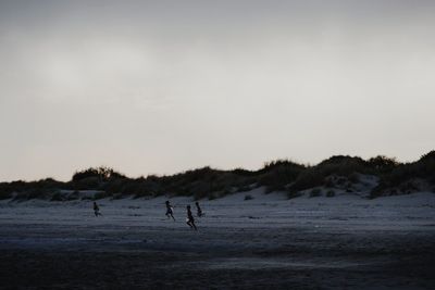 People playing on beach against sky