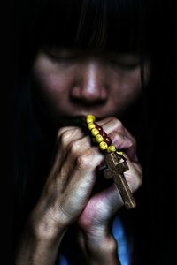 Woman holding rosary against black background