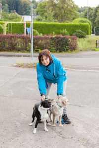 Portrait of woman with dog standing on road