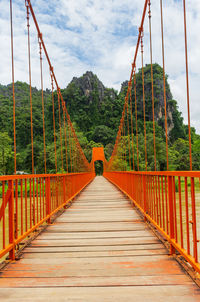 Footbridge amidst trees against sky