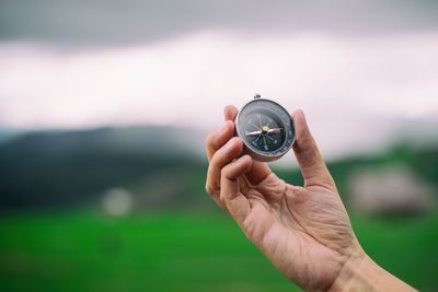 Cropped image of hand holding navigational compass