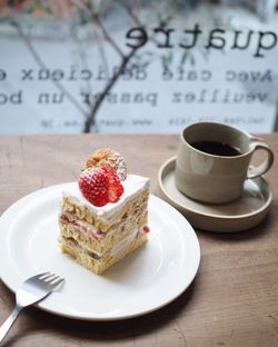 Cake on plate by coffee cup on table