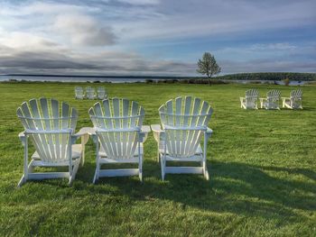 Chairs on grass against sky