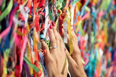 A person's hands are tying a souvenir ribbon on the railing of the senhor do bonfim church 