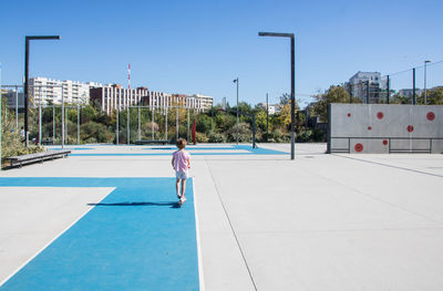 Rear view of girl with a scooter on a playground against sky