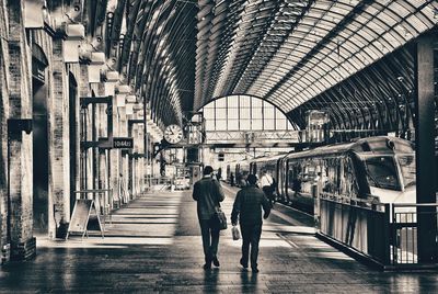 Rear view of people walking on railroad station platform