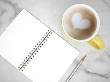 Coffee cup and notebook on marble table