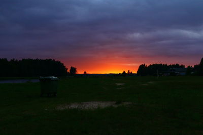 Silhouette trees on field against sky at sunset