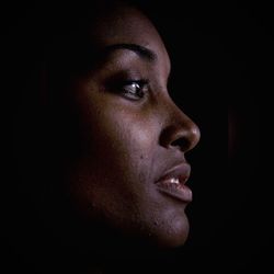 Close-up of young woman against black background