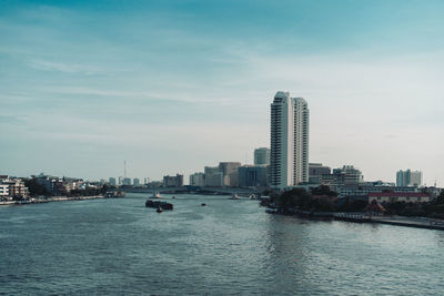 Buildings by river against sky in city