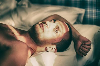 Portrait of man lying on bed at home