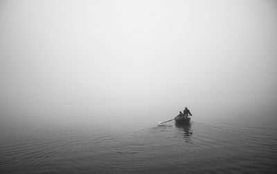 People on boat in sea against sky