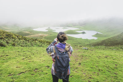 Woman with backpack standing at volcanic crater corvo, azores, portugal