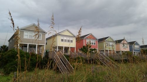 Houses by grass against sky