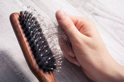 Close-up of hand removing hair from brush on table