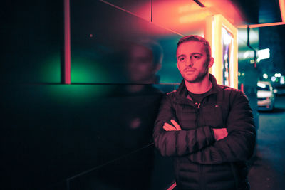 Young man standing on footpath against building at night