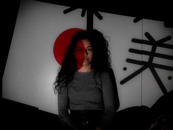 Portrait of young woman standing against wall at home