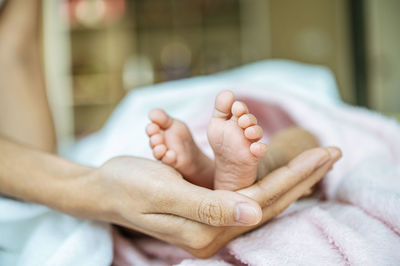 Low section of baby lying on bed