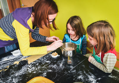 High angle view of mother with daughters preparing food in kitchen