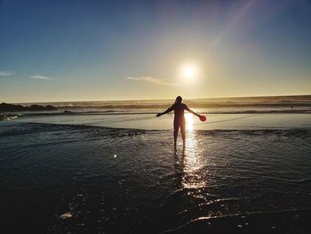 Silhouette woman on beach against sky during sunset