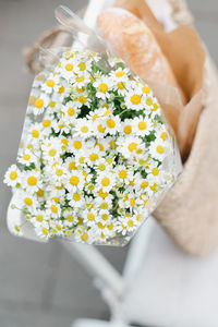 Bouquet of chamomile in a straw bag on a chair outdoors.