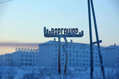 Information sign on snow covered land against clear sky