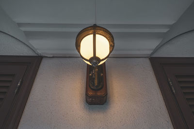 Low angle view of illuminated lamp on wall