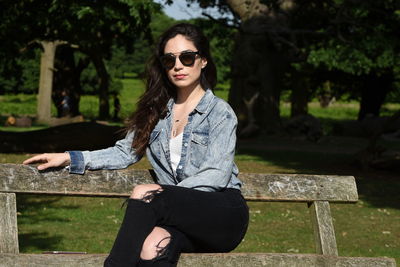 Portrait of beautiful woman sitting on wooden bench at park
