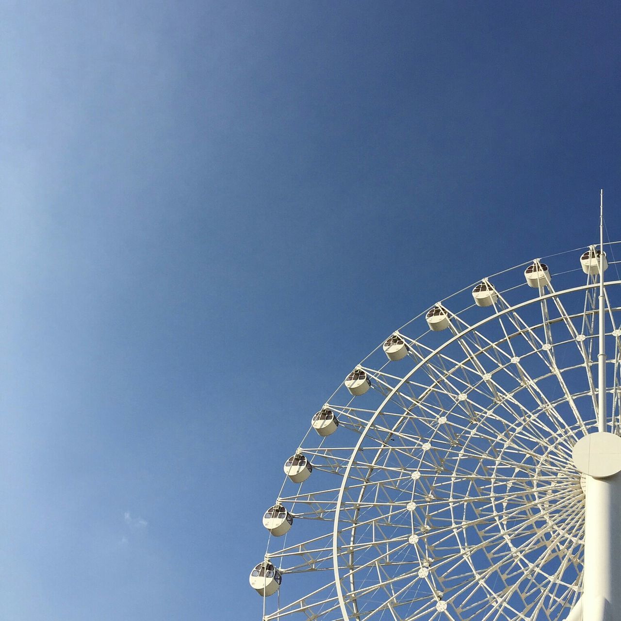 low angle view, ferris wheel, amusement park, amusement park ride, arts culture and entertainment, clear sky, built structure, sky, architecture, blue, copy space, pattern, circle, metal, outdoors, geometric shape, day, no people, fun, high section