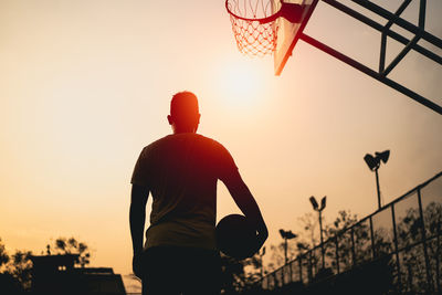 Low angle view of man standing against sky during sunset