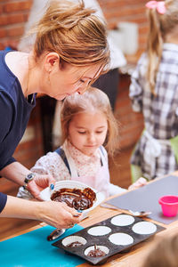 Mother with daughter preparing cupcakes at home