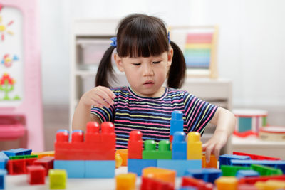 Young girl playing creative toy blocks for home schooling