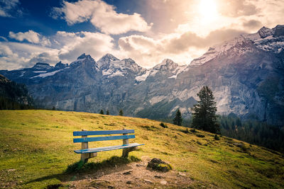 Empty bench on snowcapped mountains against sky