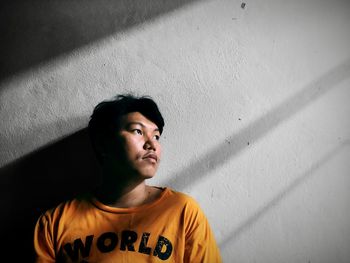 Portrait of young woman standing against wall