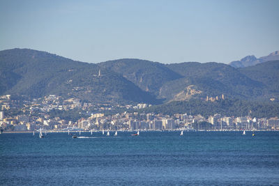 Scenic view of sea by mountains against clear sky