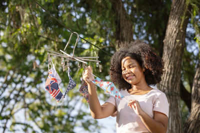 Teenage girl hanging reusable fabric protective face masks outdoors in a sunny day,