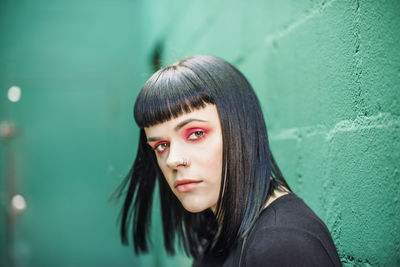 Portrait of young woman wearing make-up against wall