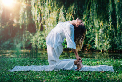 Yoga. woman doing yoga by the lake, green background.