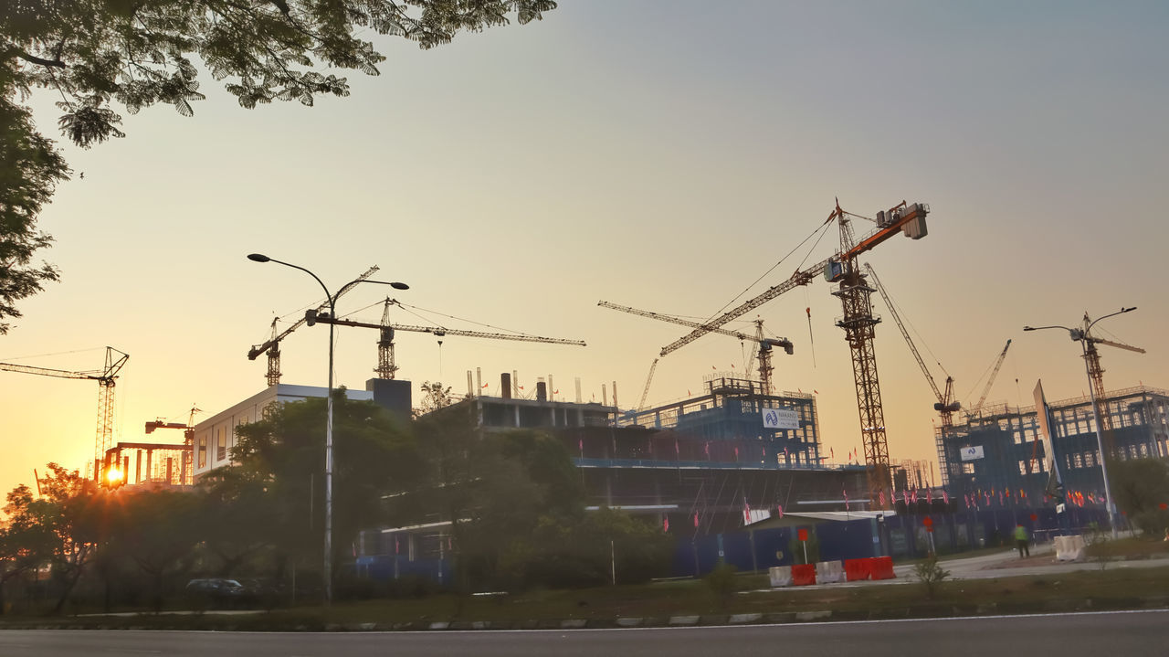 CRANES AT CONSTRUCTION SITE AGAINST SKY