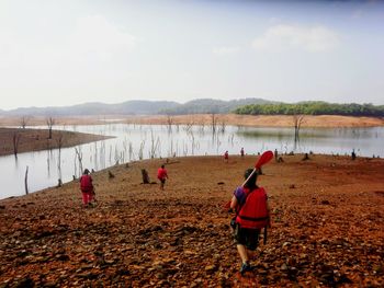 Rear view of people standing on mountain against sky