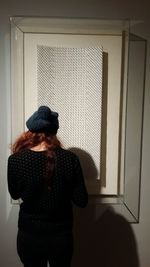 Rear view of woman standing against door at home