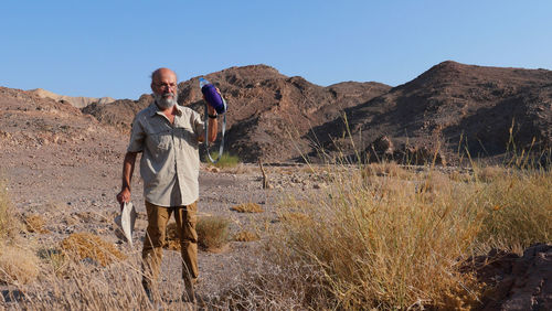 Senior man drinking water in the desert 