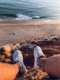 Low section of man sitting on beach