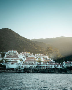 Scenic view of sea by buildings against clear sky