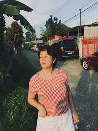 Young woman standing against plants