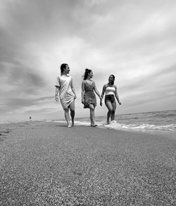 Rear view of people on beach against sky