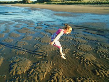 High angle view of girl jumping at beach 