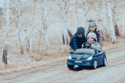 Three happy children playing with big old toy car in countryside, outdoors.