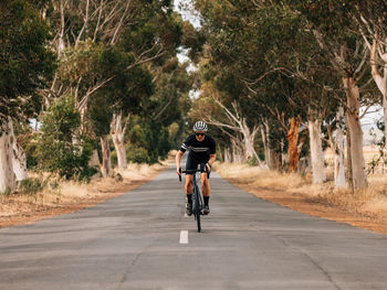 Full length of woman riding bicycle on road