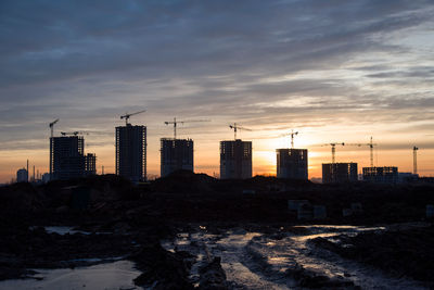 Buildings in city against sky during sunset